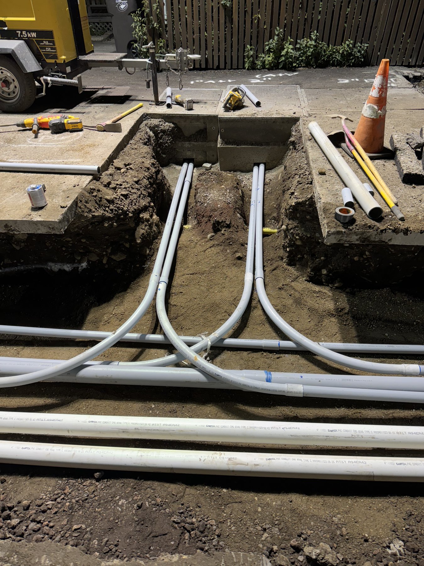 Finished utility conduit run with multiple PVC conduits routed into a vault box in an open trench